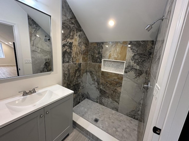 bathroom with tiled shower and vanity