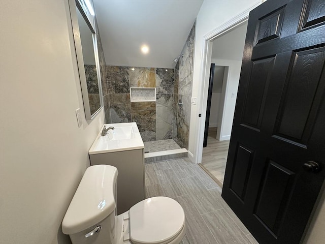 bathroom with tiled shower, vanity, and toilet