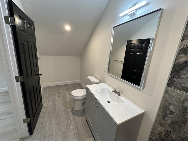 bathroom featuring lofted ceiling, vanity, and toilet