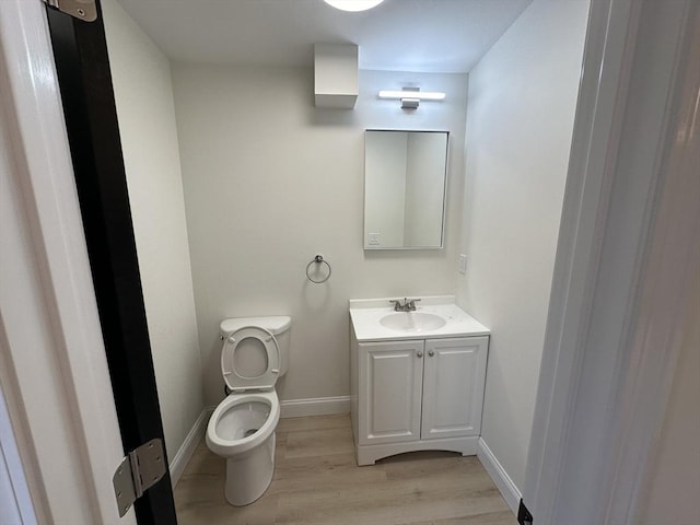 bathroom featuring wood-type flooring, toilet, and vanity