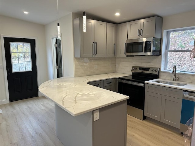 kitchen featuring stainless steel appliances, sink, gray cabinets, and kitchen peninsula