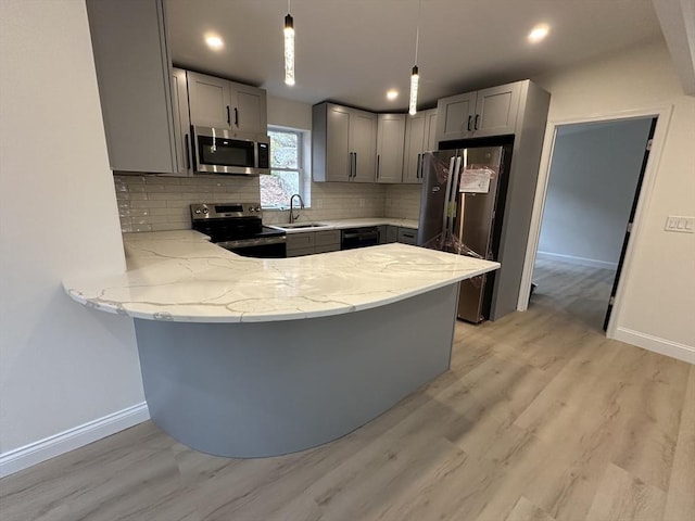 kitchen with appliances with stainless steel finishes, sink, pendant lighting, and kitchen peninsula