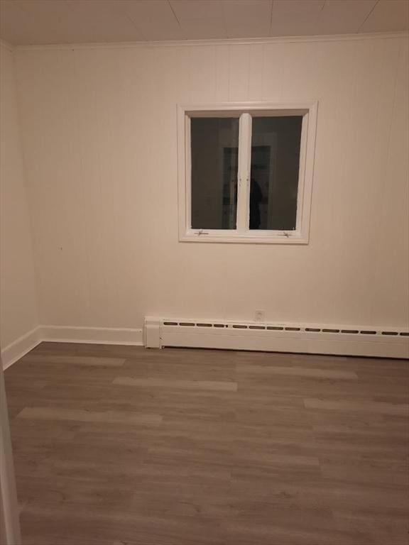 unfurnished room with ornamental molding, dark wood-type flooring, and baseboard heating