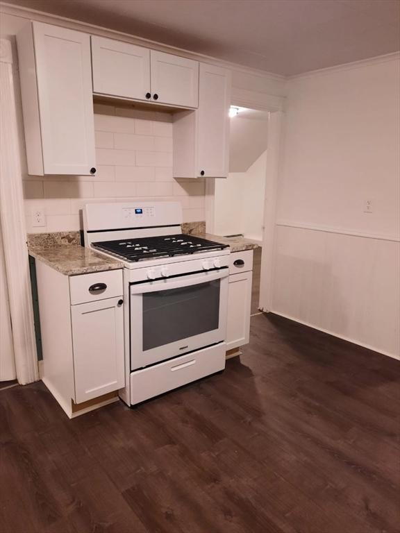 kitchen with crown molding, gas range gas stove, backsplash, dark hardwood / wood-style floors, and white cabinets