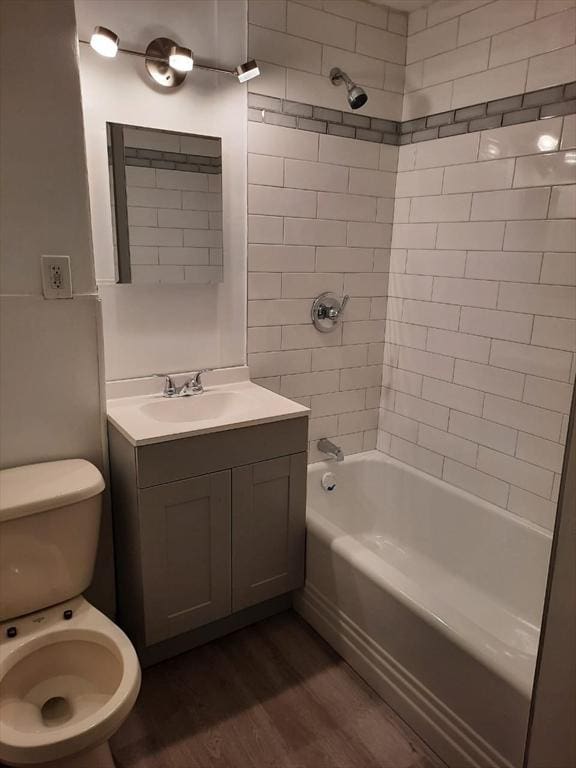 full bathroom featuring wood-type flooring, toilet, vanity, and tiled shower / bath