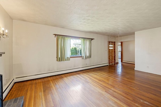 unfurnished room featuring an inviting chandelier, hardwood / wood-style flooring, a baseboard heating unit, baseboard heating, and a textured ceiling
