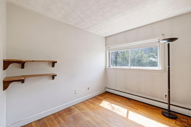unfurnished room featuring a baseboard radiator, light wood-style flooring, and baseboards