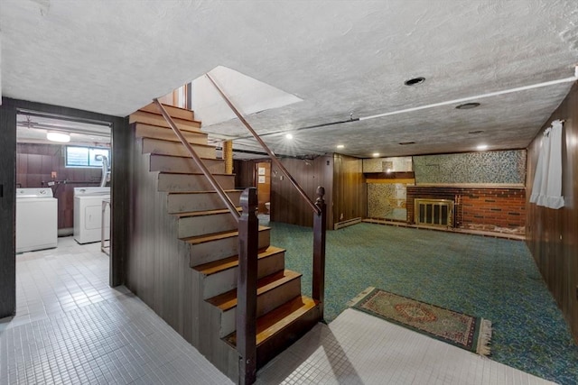 basement with wood walls, stairway, washer and clothes dryer, and a fireplace