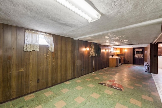 basement featuring tile patterned floors, wooden walls, and a textured ceiling