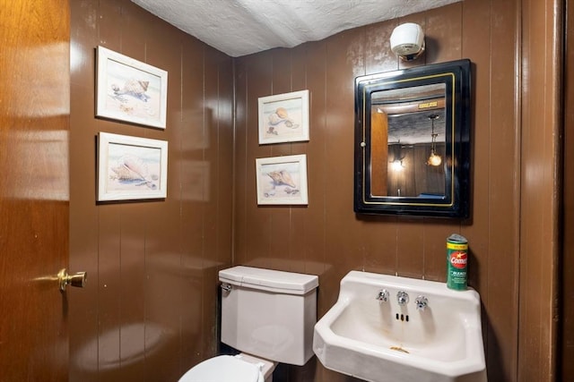 half bath featuring toilet, a textured ceiling, and a sink