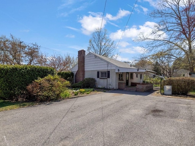 view of property exterior with a chimney and aphalt driveway