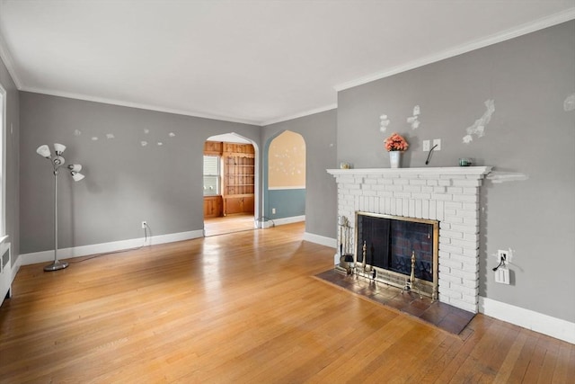 229 May St, Worcester, MA 01602 - unfurnished living room with arched walkways, a brick fireplace, wood finished floors, baseboards, and ornamental molding