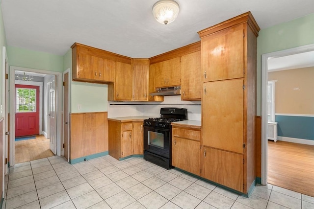 229 May St, Worcester, MA 01602 - kitchen featuring gas stove, under cabinet range hood, light countertops, light tile patterned floors, and wainscoting