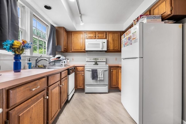 7 Hovey Pond Dr Unit 7, Grafton, MA 01536 - kitchen with white appliances, brown cabinetry, light wood finished floors, light countertops, and a sink