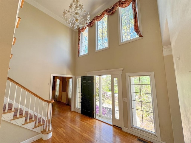 foyer entrance with stairway, a chandelier, a towering ceiling, and wood finished floors