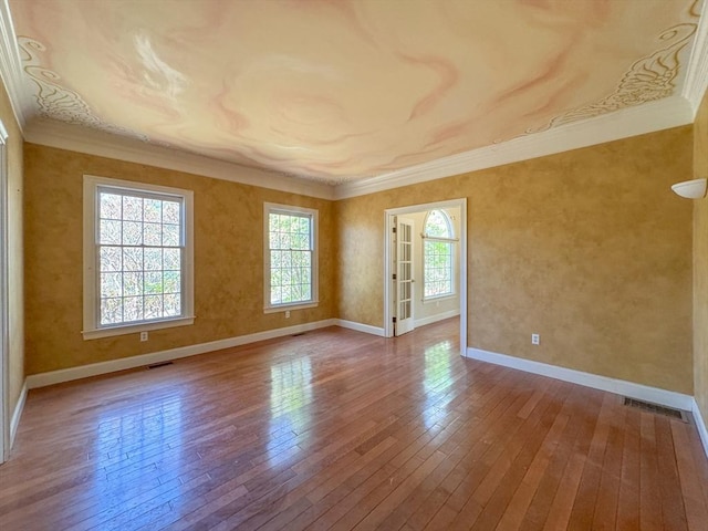 unfurnished room featuring ornamental molding, baseboards, hardwood / wood-style floors, and visible vents