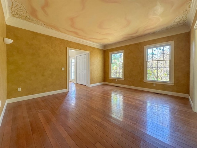 spare room with baseboards, wood-type flooring, and crown molding