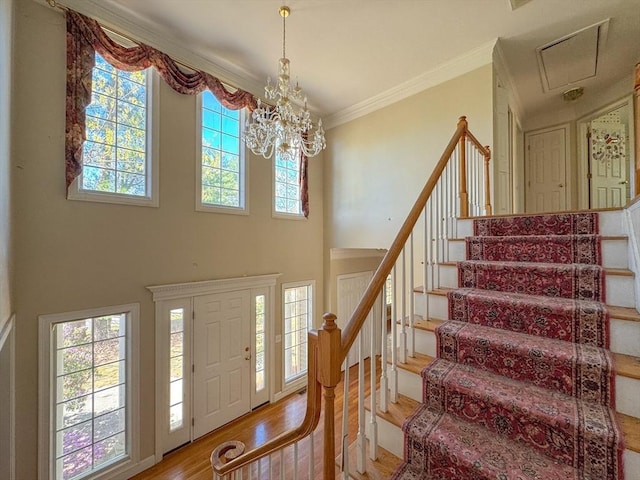 entrance foyer featuring a notable chandelier, stairway, a healthy amount of sunlight, and wood finished floors
