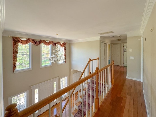 hallway featuring baseboards, ornamental molding, visible vents, hardwood / wood-style flooring, and an upstairs landing