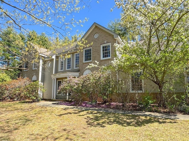 traditional home with brick siding and a front lawn