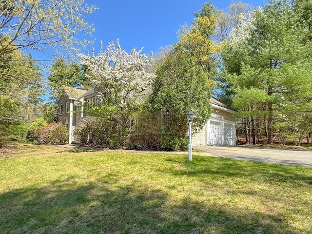 view of front of home with a front yard, aphalt driveway, and a garage