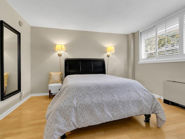 bedroom featuring hardwood / wood-style flooring and radiator heating unit