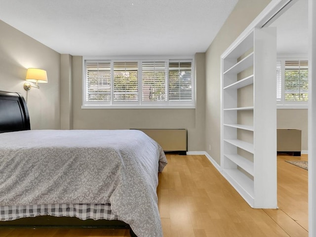 bedroom with radiator heating unit and light wood-type flooring