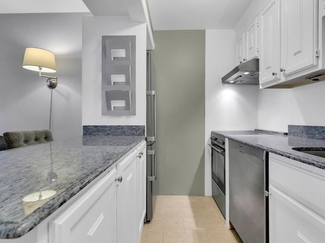 kitchen featuring white cabinets, stainless steel appliances, dark stone countertops, kitchen peninsula, and light tile patterned flooring