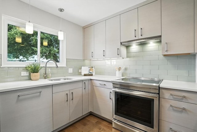 109 Governor Winthrop Rd Unit 109, Somerville, MA 02145 - kitchen with stainless steel range with electric stovetop, dark wood finished floors, light countertops, backsplash, and decorative light fixtures