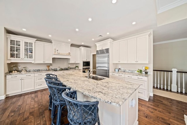 31 Chittenden Ln Unit 31, Cohasset, MA 02025 - kitchen featuring built in appliances, a center island with sink, ornamental molding, dark wood finished floors, and white cabinetry