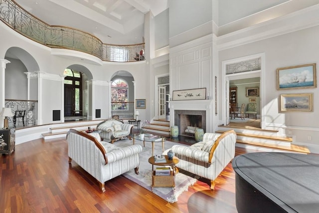 11 Fairway Dr, Andover, MA 01810 - living area featuring ornate columns, a high ceiling, a fireplace, wood finished floors, and arched walkways