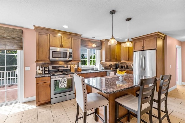 169 Braeburn Rd, East Longmeadow, MA 01128 - kitchen featuring appliances with stainless steel finishes, backsplash, a kitchen breakfast bar, brown cabinets, and baseboards