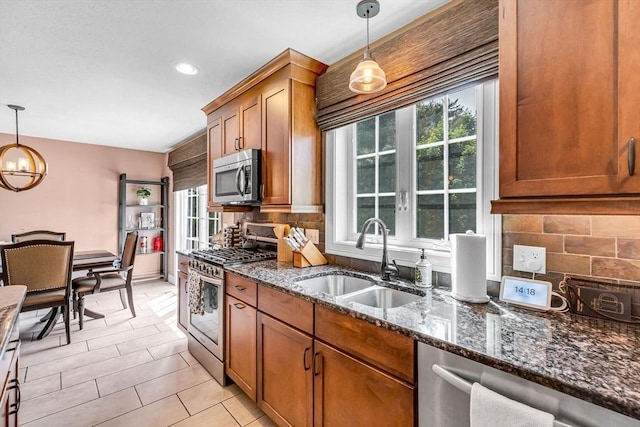 169 Braeburn Rd, East Longmeadow, MA 01128 - kitchen featuring appliances with stainless steel finishes, a sink, brown cabinetry, decorative backsplash, and dark stone countertops