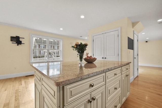 kitchen featuring light wood-type flooring, cream cabinetry, and baseboards