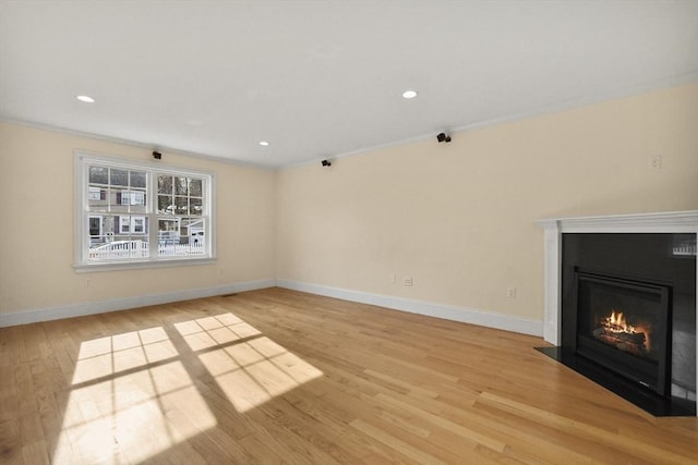 unfurnished living room with recessed lighting, light wood-style flooring, baseboards, and a fireplace with flush hearth