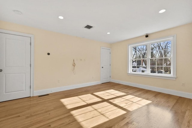 empty room with wood finished floors, visible vents, and baseboards