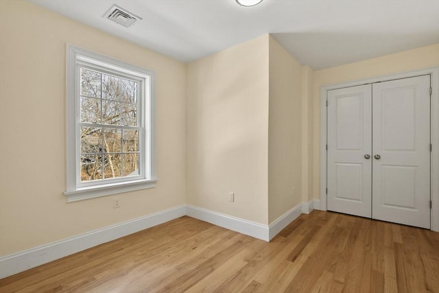 unfurnished bedroom with light wood-style floors, a closet, visible vents, and baseboards