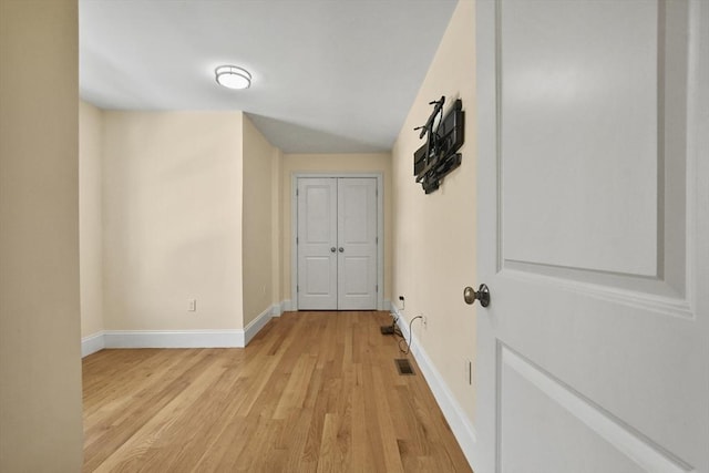 hallway featuring light wood-type flooring, visible vents, and baseboards