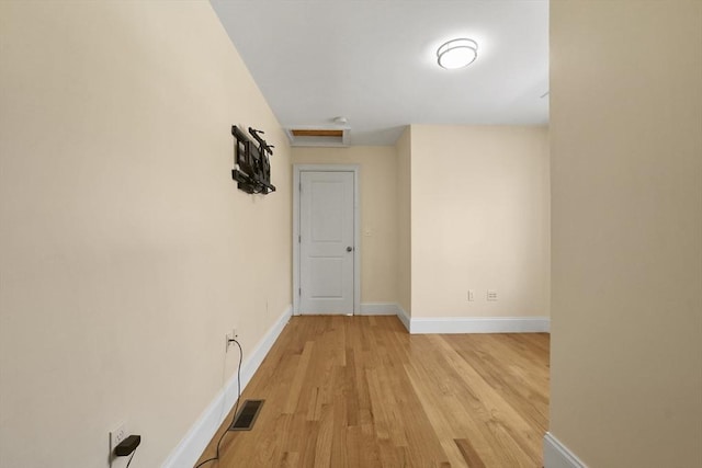 interior space featuring attic access, visible vents, light wood-style flooring, and baseboards