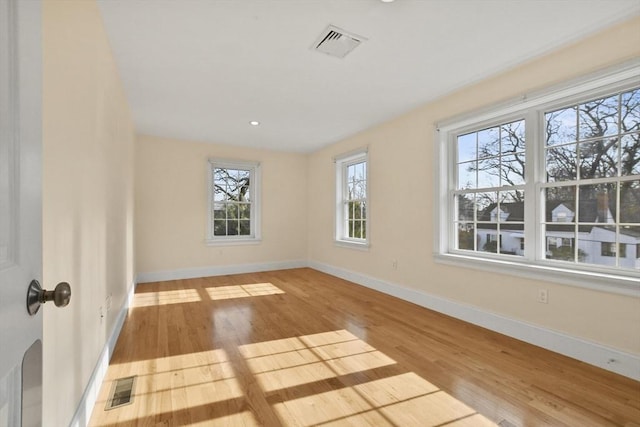 unfurnished room featuring baseboards, visible vents, and wood finished floors