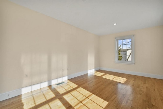 empty room featuring visible vents, baseboards, and wood finished floors