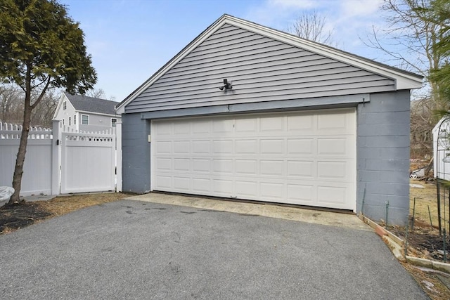 detached garage with a gate and fence