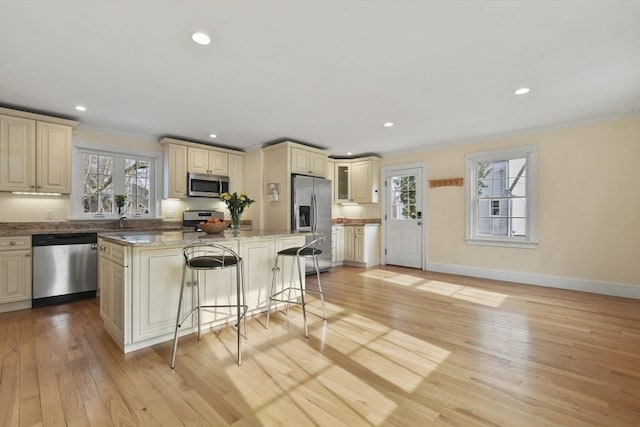 kitchen featuring stainless steel appliances, a center island, a healthy amount of sunlight, and cream cabinets