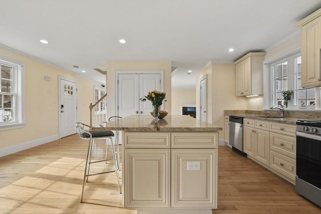 kitchen featuring light stone countertops, a kitchen island, appliances with stainless steel finishes, and cream cabinetry