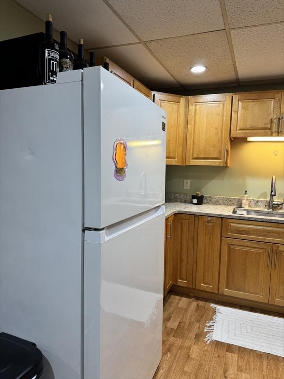 16 Richards Ave Unit 106, North Attleboro, MA 02760 - kitchen with a sink, light countertops, freestanding refrigerator, a drop ceiling, and light wood-style flooring