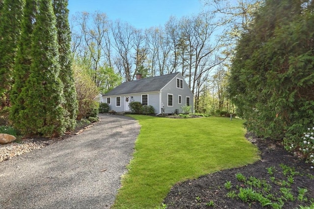 view of front facade with a chimney, a front lawn, and driveway