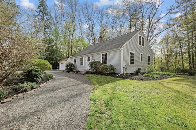 view of front of home with a chimney, an outdoor structure, a front yard, and a detached garage