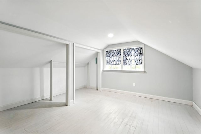 additional living space featuring baseboards, lofted ceiling, and wood finished floors