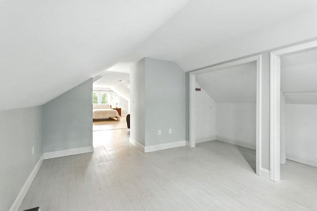 bonus room featuring lofted ceiling, light wood-style flooring, and baseboards