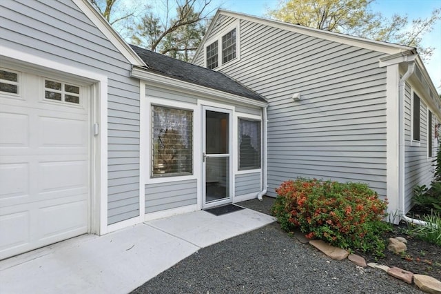property entrance with roof with shingles and a garage